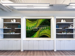 Modern corporate office interior with a large preserved moss wall and sleek reception desk.