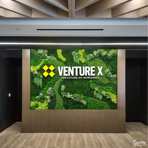 A modern corporate office lobby featuring a vibrant preserved moss wall with faux succulents and sleek contemporary furniture.
