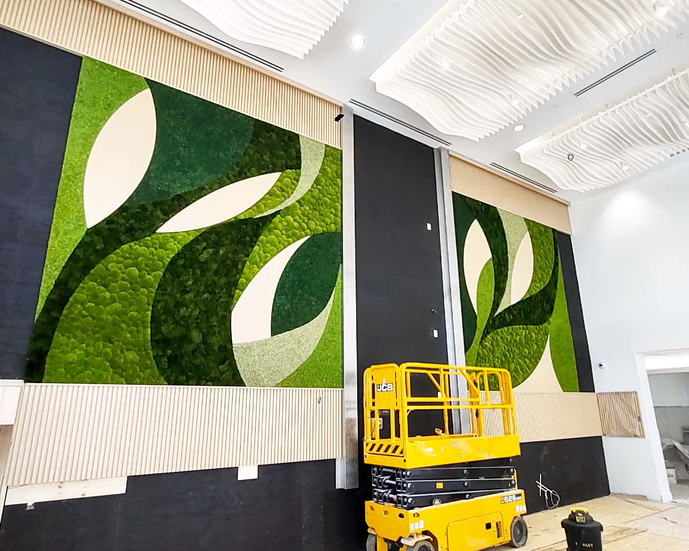 Large green leaf-patterned moss wall panels in a modern interior setting with a yellow lift.